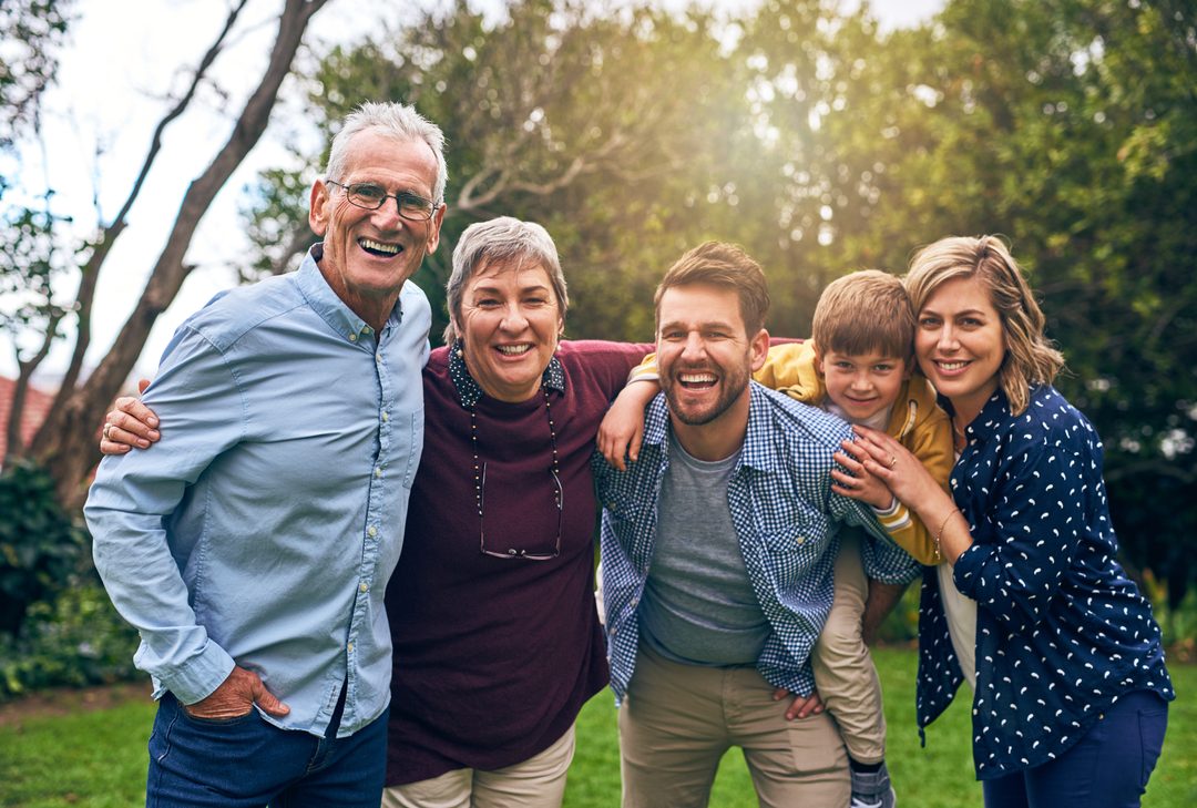 A multigenerational family smiling together outdoors